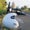 capacete a frente e moto jogada ao fundo
