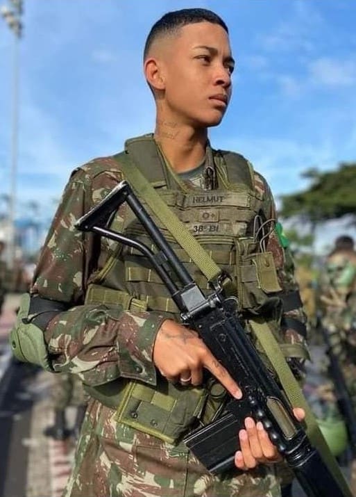 Ex-soldado segurando um fuzil, pousando para foto.