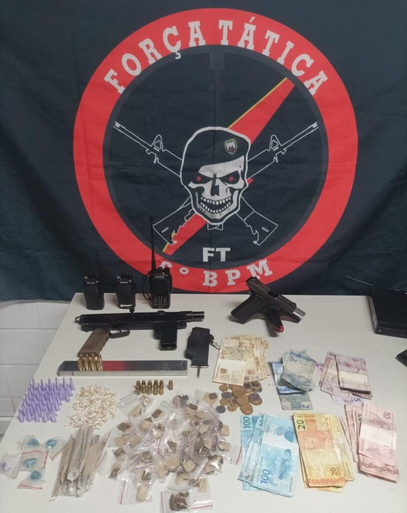 Foto da mesa onde foram expostas as apreensões da Força Tatica com duas armas, drogas e dinheiro.