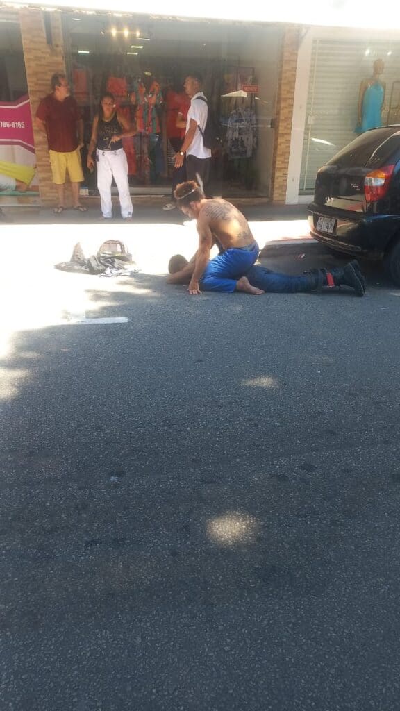 Imagem de um homem (Professor de jiu-jitsu) imobilizando um sujeito deitado no chão que tentou roubar um carro.