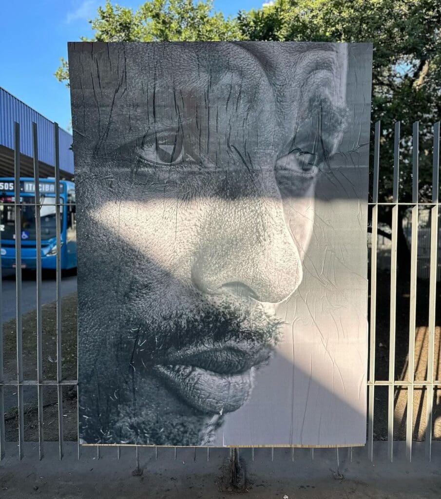 Foto de um painel com uma foto preta e branco colocada nas grades de um terminal de ônibus.