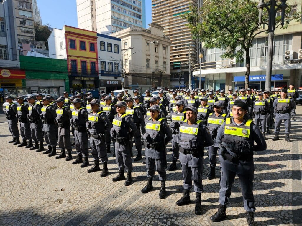 Policiais militares enfileirados em uma praça durante uma formatura de novos soldados.