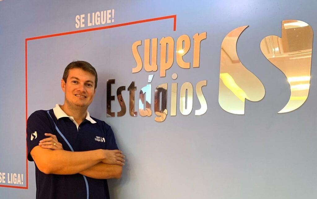 Vitor Aguiar Corteletti, diretor da Super Estágios do Espírito Santo, proximo a uma parede onde a o símbolo da Super Estágio.