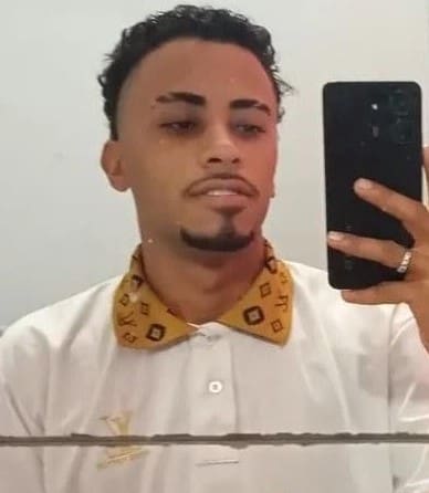 Um jovem segurando um celular (João Lucas Souza da Silva, 21 anos)