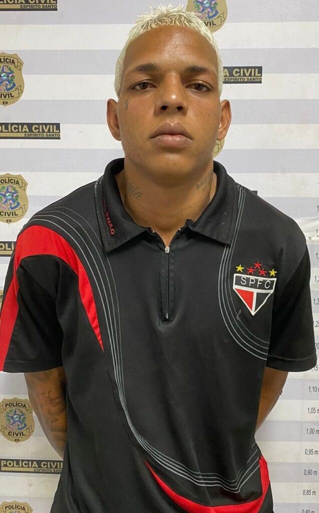 Um homem (João Lucas Souza da Silva) posando para a foto no fundo um banner da Polícia Civil