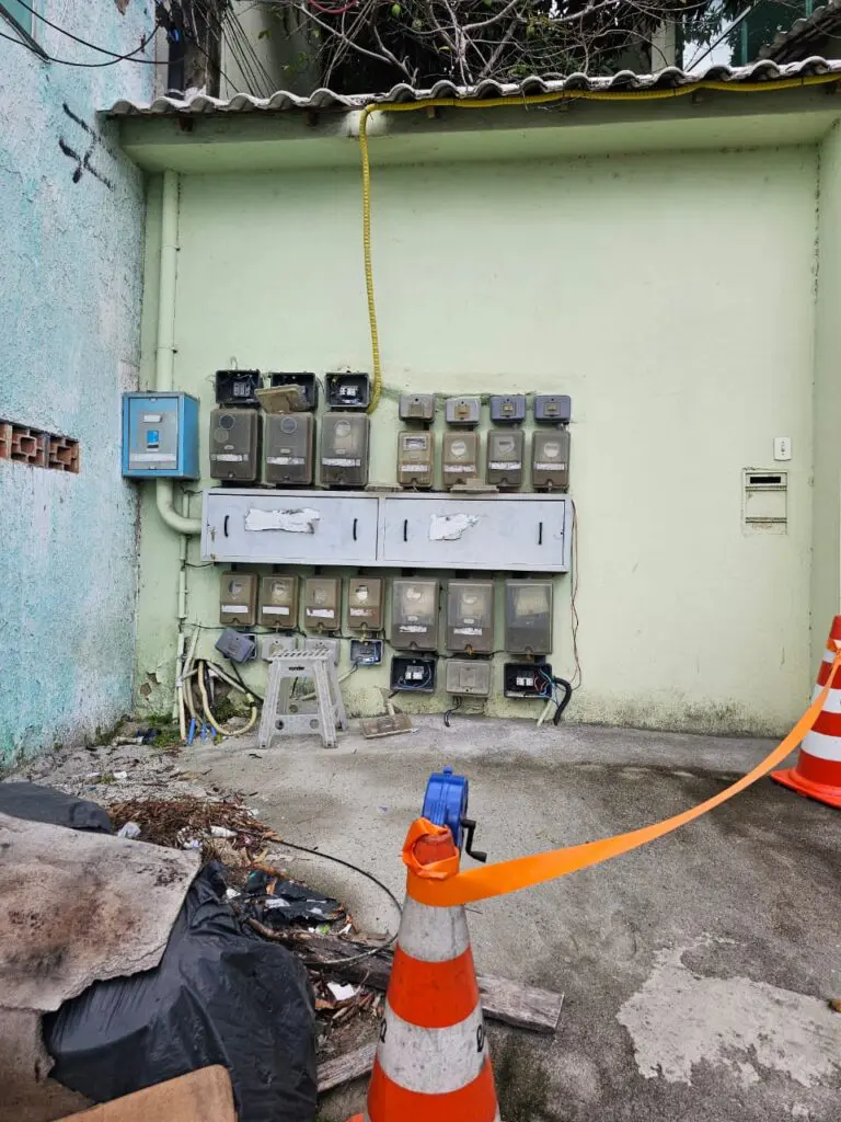 Um local com diversas caixas de medição de energia, com um cone e uma fita isolando o local.