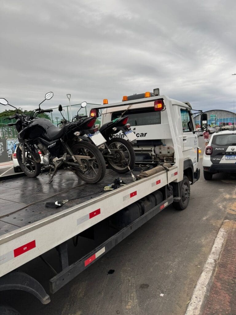 Um caminhão guincho, com duas motocicletas sobre sua rampa apreendidas durante a ação da Polícia Militar.