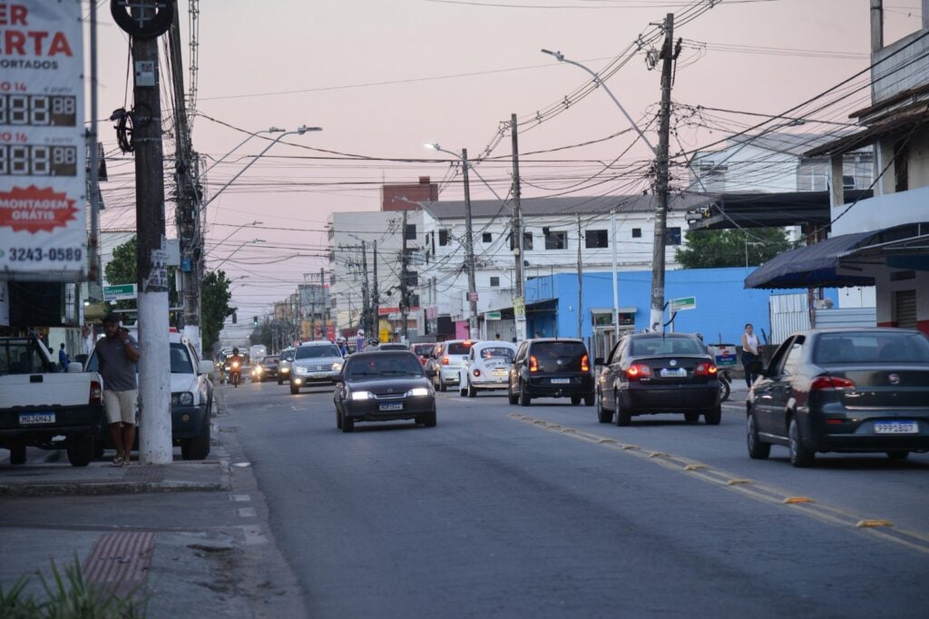 Imagem de uma avenida com carros trafegando em duas pistas em direções diferentes.