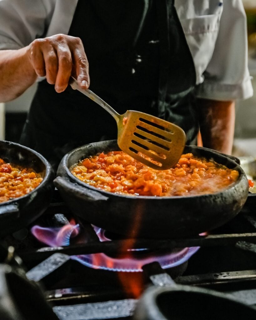 Imagem de um cozinheiro de avental preparando uma Moqueca capixaba - Preparada na Cozinha do Restaurante Pirão.