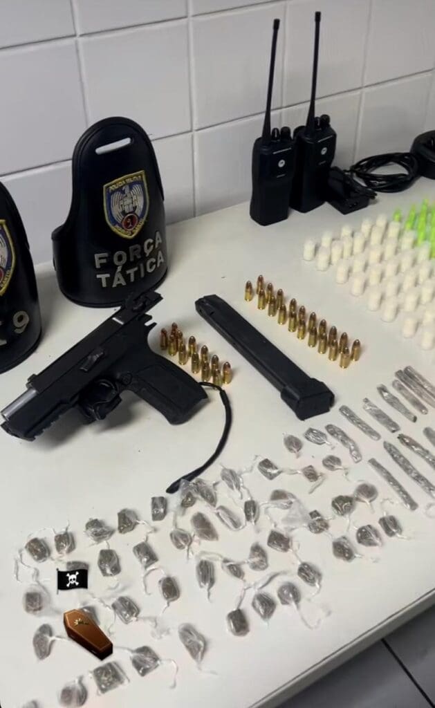 Sobre uma mesa uma pistola munições e diversas unidades de drogas.