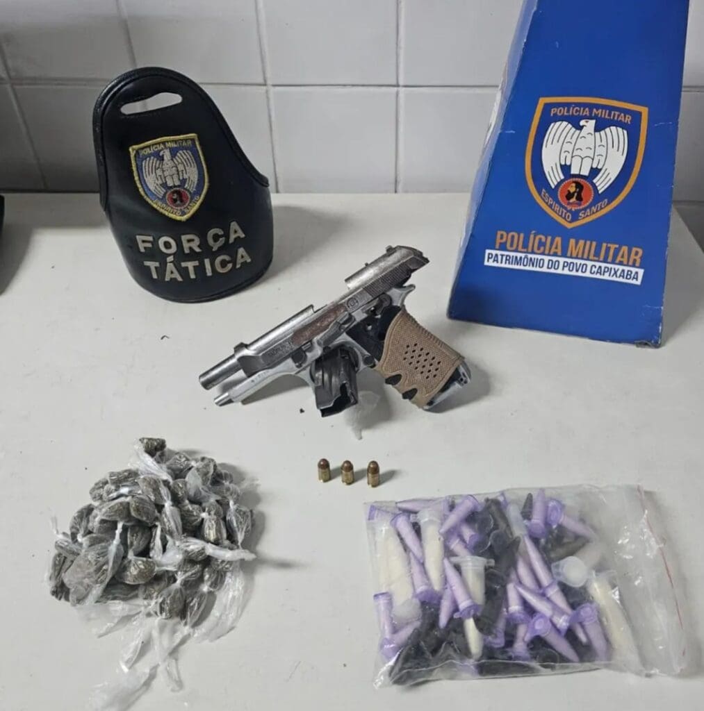 Sobre uma mesa uma pistola calibre .380, 60 buchas de maconha e 82 pinos de cocaína.