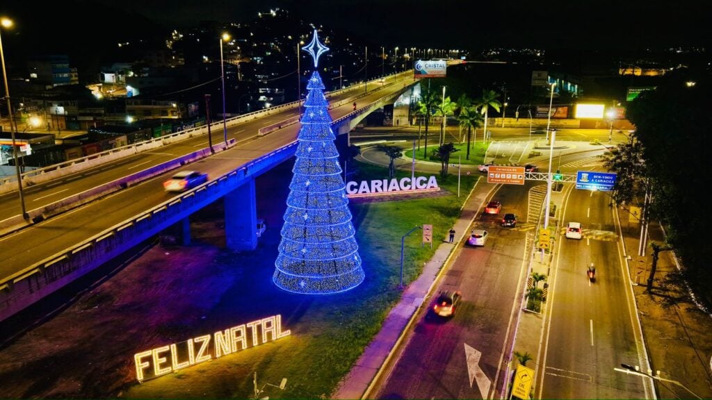 Imagem de uma ponte com uma praça ao lado com uma arvore de Natal, e outras decorações natalinas.