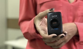 Uma mulher segurando um objeto com um botão do pânico.