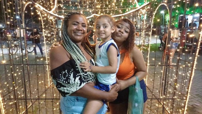 Imagem de duas mulheres segurando uma criança enquanto posam para uma foto.