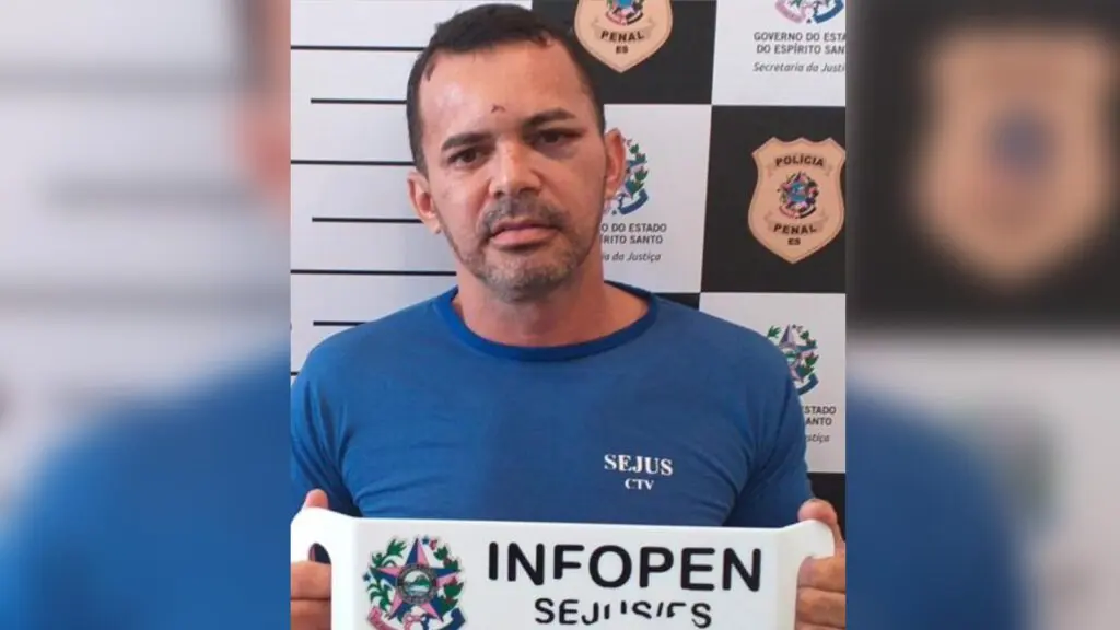 Assessores do gabinete do vereador Fred são exonerados da Câmara da Serra Vereador Fred do PDT sendo fichado com uniforme azul da SEJUS, segurando a placa e machucados visíveis no rosto