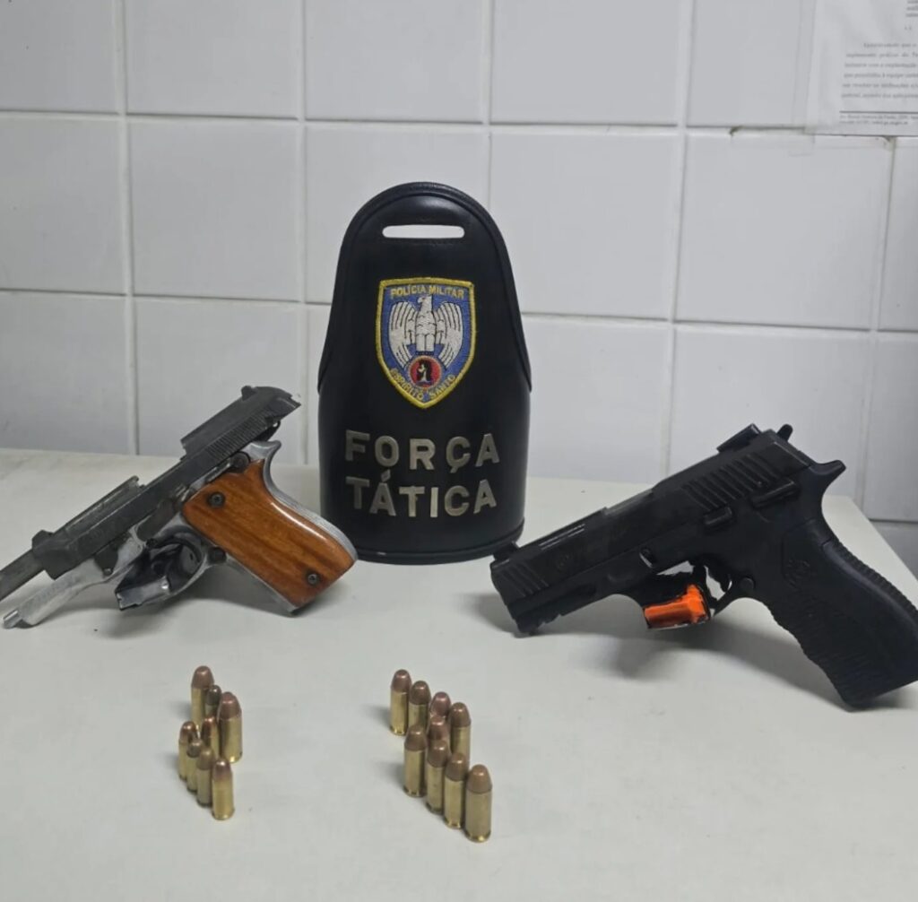 Duas armas (pistolas) apreendidas sobre uma mesa durante a ocorrência. 
