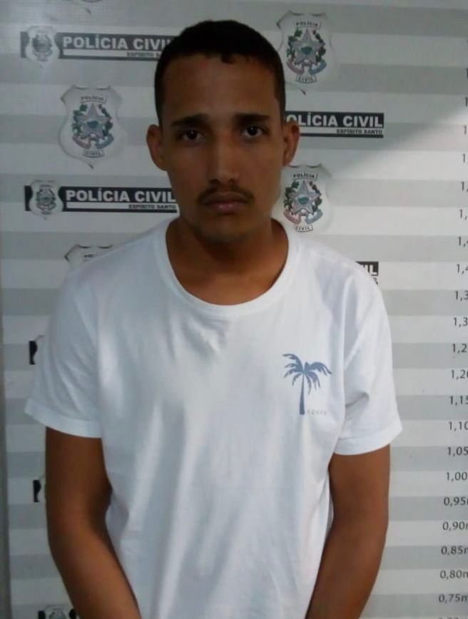 Imagem de um homem (Kaciano Silva Damasceno) em frente a uma parede com informações da Polícia Civil e marcações de altura.