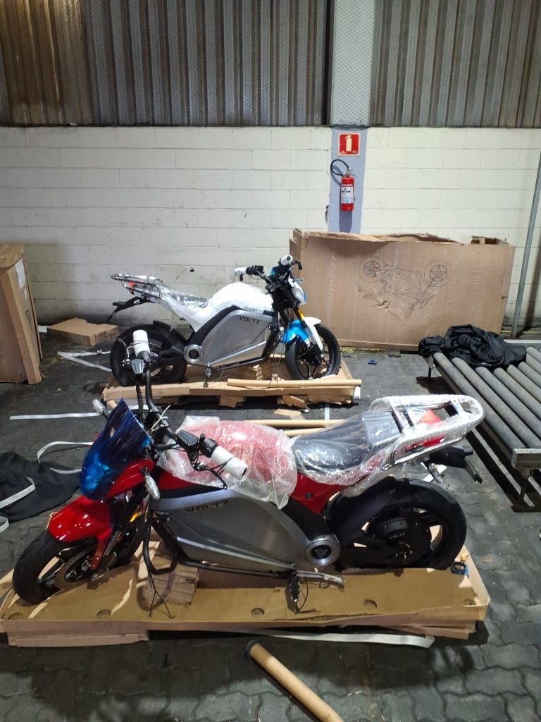 Imagens de duas motocicletas elétricas Voltz EVS Work estacionadas em um galpão.