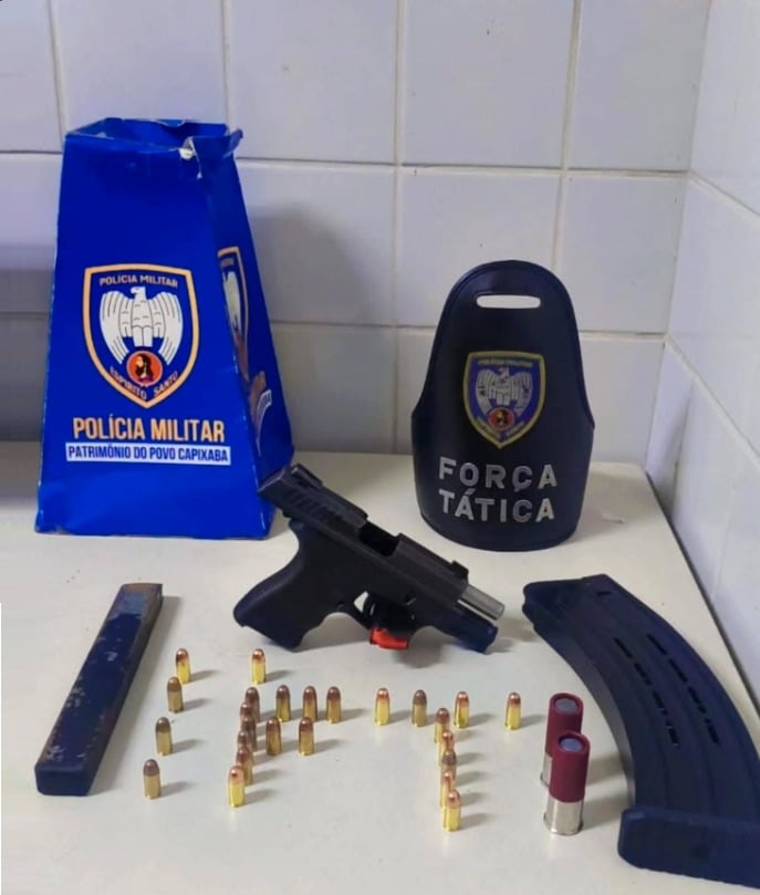 Sobre uma mesa, uma pistola calibre 9mm, dois carregadores, sendo um de calibre 12 e outro de fabricação caseira, além de 25 munições de calibre 9mm e dois cartuchos de calibre 12.